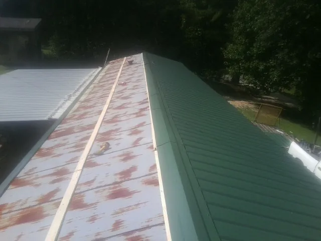 Old rusted panels beside newly installed green metal roofing — Wind Damage Roof Repair by Roofing Brothers in Veradale