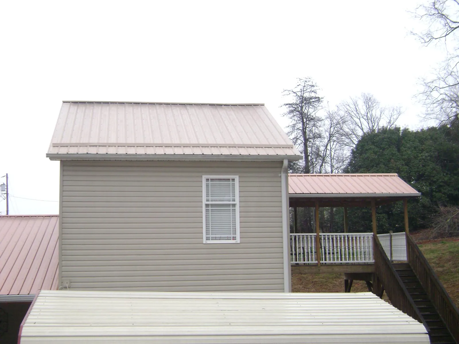 Tan metal roofs on a two story addition and attached porch, from a Roof Replacement job in Veradale