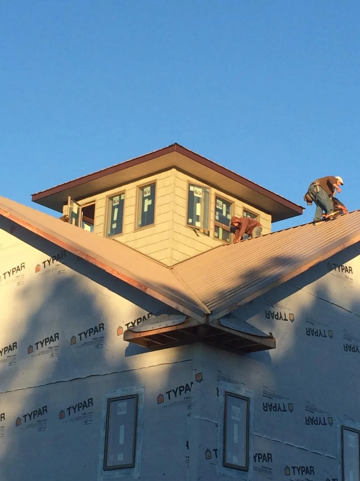 Roofers working around a rooftop cupola on a new metal roof at sunset — Roof Waterproofing in Veradale by Roofing Brothers